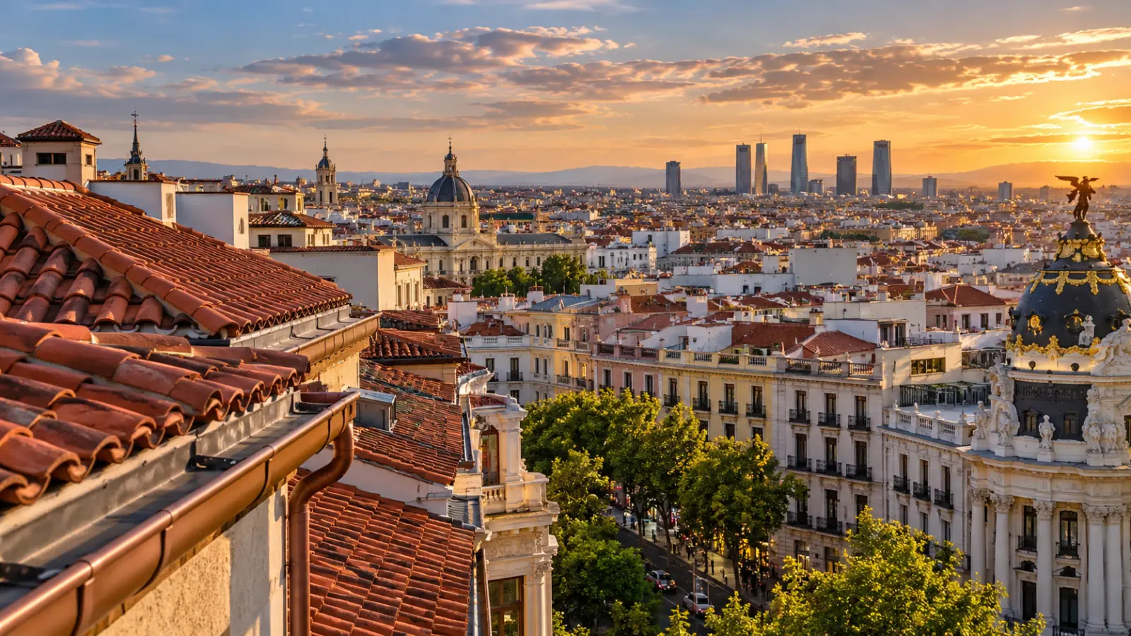 Vista de tejados de teja y canalón al atardecer en el centro de Madrid, con el perfil de la ciudad al fondo